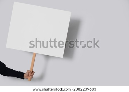 Woman holding blank sign on light grey background, closeup. Space for text Royalty-Free Stock Photo #2082239683