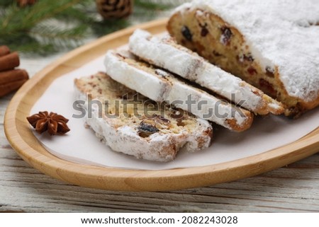 Traditional Christmas Stollen with icing sugar on white wooden table, closeup