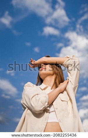 Portrait of a young girl against a background of blue sky and clouds. Royalty-Free Stock Photo #2082255436