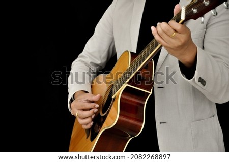 guitarist playing acoustic guitar on black background(selective focus).concept to music magazine,music instrument, advertising etc.