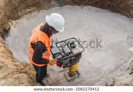 Worker uses a portable vibration rammer at construction of a power transmission substation Royalty-Free Stock Photo #2082270412