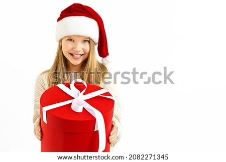 beautiful girl, child, girl portrait, in a red santa claus hat, on a white background, isolate, holding a red gift box, smiling happy, place for text banner, sale, discounts	