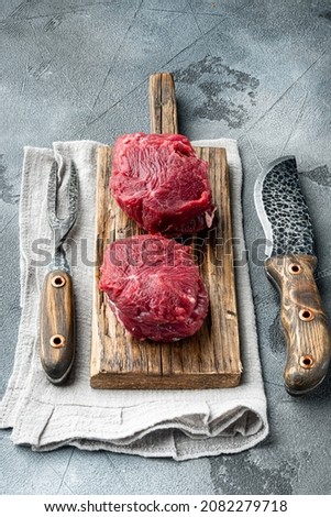 Fresh raw fillet minion steaks marbled beef with rosemary and garlic set, on wooden cutting board, on gray stone background