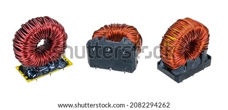 Closeup of various electronic toroidal coils isolated on white panoramic background. Set of red inductors with copper wire winding in sockets encased by black epoxy resin. Electrotechnical components. Royalty-Free Stock Photo #2082294262