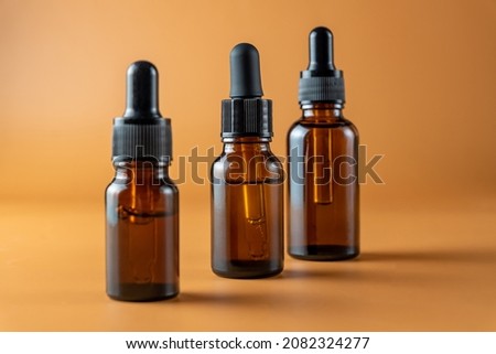 Set of brown glass bottles with essential oil on a beige background. Packaging of a beauty product with a pipette for alternative medicine treatment. Aromatherapy, homeopathy. Unbranded package.