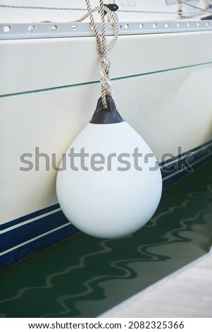 White fenders suspended between a boat and dockside for protection. Maritime fenders Royalty-Free Stock Photo #2082325366