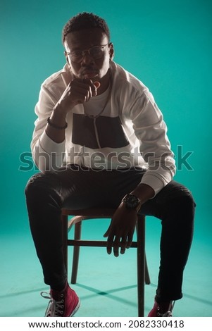 Attractive and handsome black male is having a great posture while sitting and posing on the chair