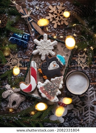 Christmas background. Fragrant honey gingerbread cookies in the form of a snowflake, a penguin, a Christmas tree near fir branches and New Year's decor on a wooden table.