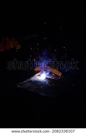Welding metal with sparks. A man's hand in a glove with welding equipment welds metal structures. 