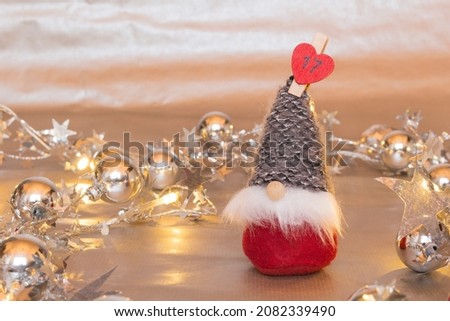 Tomte, the Swedish Santa Claus, with long white beard, conical knit gray cap and red suit. Advent calendar. 17 December. Christmas decoration on sparkling silver garlands background. Place for text.