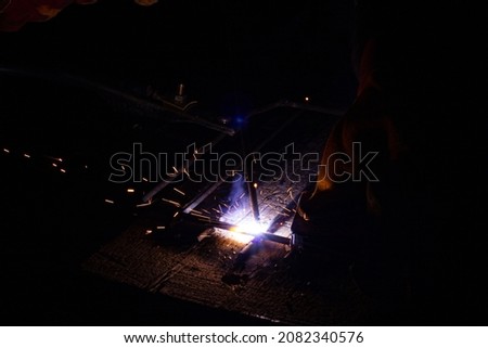 Welding metal with sparks. A man's hand in a glove with welding equipment welds metal structures. 