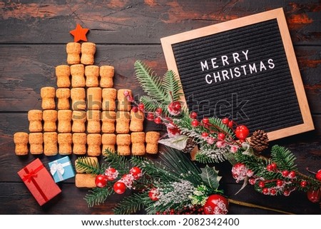 Christmas tree with red star made from wine or champagne corks on rustic wooden table near letter board with words Merry Christmas and decorations.