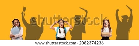 Three cute schoolgirls with books dreaming about graduation, standing on orange background with drawn shapes of happy females graduating behind their back, panorama, collage, kids dreams concept Royalty-Free Stock Photo #2082374236