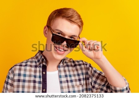 Photo of young cheerful guy hand touch eyeglasses cool ginger hair isolated over yellow color background