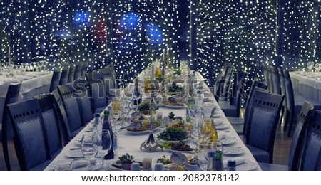 Photo for congratulations on Christmas and New City - 2023. Festive table: candle, glasses, plates, dishes, wine, etc.