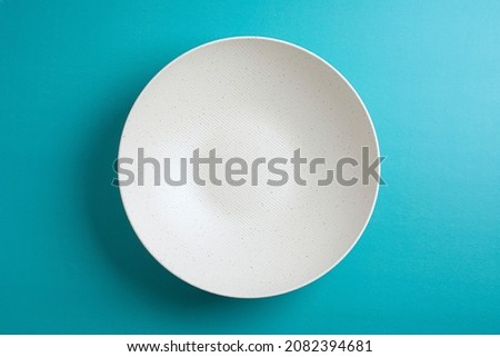 Top down minimalist view of a white bowl on yellow background. White round plate on blue background	 Royalty-Free Stock Photo #2082394681