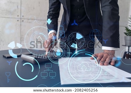 A research and development specialist computing the data to create a new approach to develop high tech business. Technological icons over the desk with calculator.