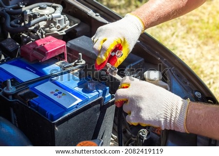 The car mechanic unscrews the car battery holder to repair or replace it. Transport service. Royalty-Free Stock Photo #2082419119