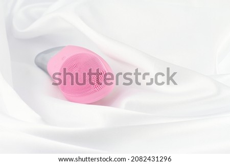 Pink facial sonic brush on white silk 