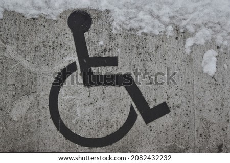 A parking sign covered with mud and snow for people with special needs