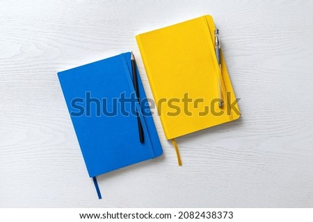 Above view at two books on table, yellow and blue hardcover with pencil and pen. Royalty-Free Stock Photo #2082438373