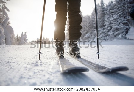 Skiing. Ski on First Tracks. Alpine skier going downhill skiing in morning on Fresh Tracks on groomed ski trail slope piste. Closeup of trail, skis and ski boots amongst snow covered trees. Royalty-Free Stock Photo #2082439054