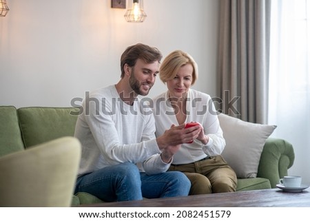 Young bearded man looking at the photos with his mom