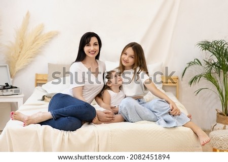 Young happy family with two girls and single mom. Mother, teenager girl and preschooler child girl sit together at their home. Family and relationship. Selective focus.