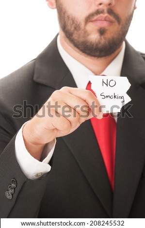 No smoking concept using a man wearing a black suit and red necktie and holding a piece of paper with the text no smoking on it.