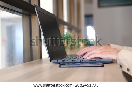 Hands of a businessman operating a laptop at his desk in a modern office, planning his business, and working online