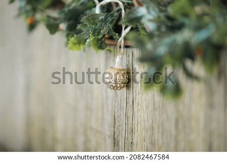 Mistletoe and delicate Christmas lights strewn along rustic wooden seat. Golden bokeh in background.