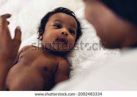 Portrait of enjoy happy love family african american mother playing and kiss with adorable little african american baby.Mom touching with cute son in a white bedroom