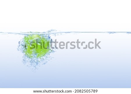 Fresh green apple falling under water splash isolated on white background.