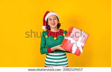 Portrait of Latin teenager girl holding Christmas gift box on a yellow background in Mexico latin america