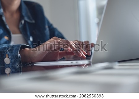 Close up of business woman, freelancer working on laptop computer with digital tablet on table at home office. Student studying online class via laptop, e-learning, working at home concept
