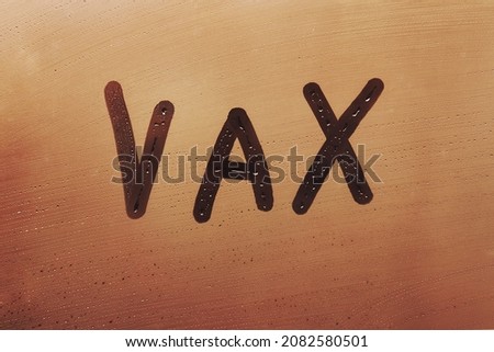 Foggy glass on window with written finger word Vax concept photo with copy space on orange background