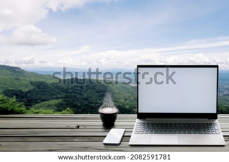 Notebook computer smartphone and hot coffee on high wooden bar on mountain, that be place for distancing network of business connection, during social distancing in Coronavirus pandemic