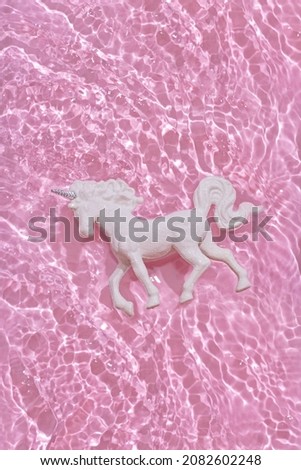 White unicorn in water on pink background
