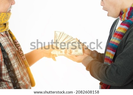 Happy senior man with scarf and santa hat give money to his son for celebrate christmas eve on white background. Dollar bills that a father gives his son for save in special day. 