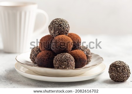 vegan energy bliss balls with chia seeds, cocoa powder and cup of hot drink. no bake raw vegan protein dessert. White background. copy space Royalty-Free Stock Photo #2082616702