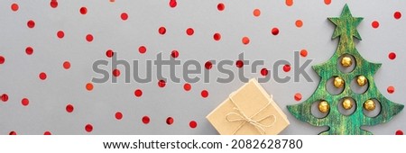 Banner with a Christmas tree, present and red confetti on a gray background. Christmas card. Flat lay, copy space.