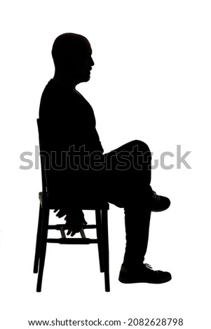 side view of  silhouette of a man sitting on chair with casual clothes legs crossed
