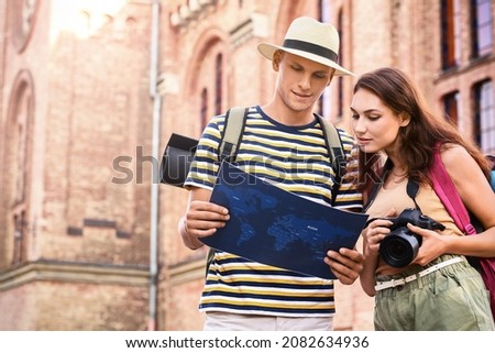 Couple of tourists with map on city street