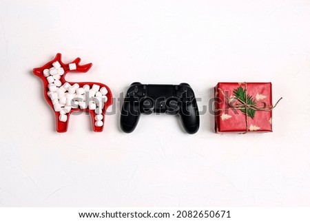 Joystick gaming controller with gift and plate deer with marshmallows on white background. Xmas holiday sale or leisure concept.