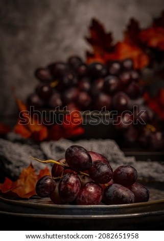 Red dark grapes with Autumn leaves. Still life photography