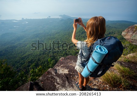 Female hiker taking picture of the valley from top of the hill
