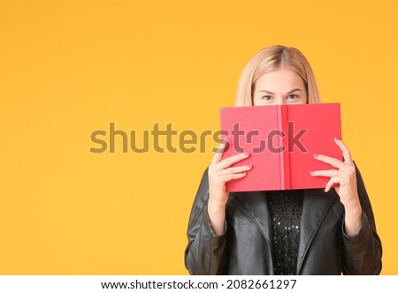 Beautiful young woman reading book on color background