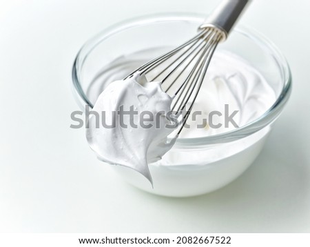 glass bowl of whipped egg whites cream on white kitchen table background Royalty-Free Stock Photo #2082667522