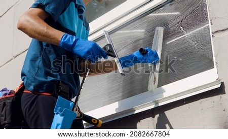 Male professional cleaning service worker in overalls cleans the windows and shop windows of a store with special equipment Royalty-Free Stock Photo #2082667804