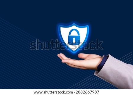 Businessman hand holds shield icon and sign of padlock on blue background. GDPR, General Data Protection Regulation, European Data Privacy Act. Copy space. High quality photo
